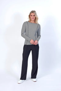 Woman wearing black and white striped long sleeve top with black pants and white sneakers
