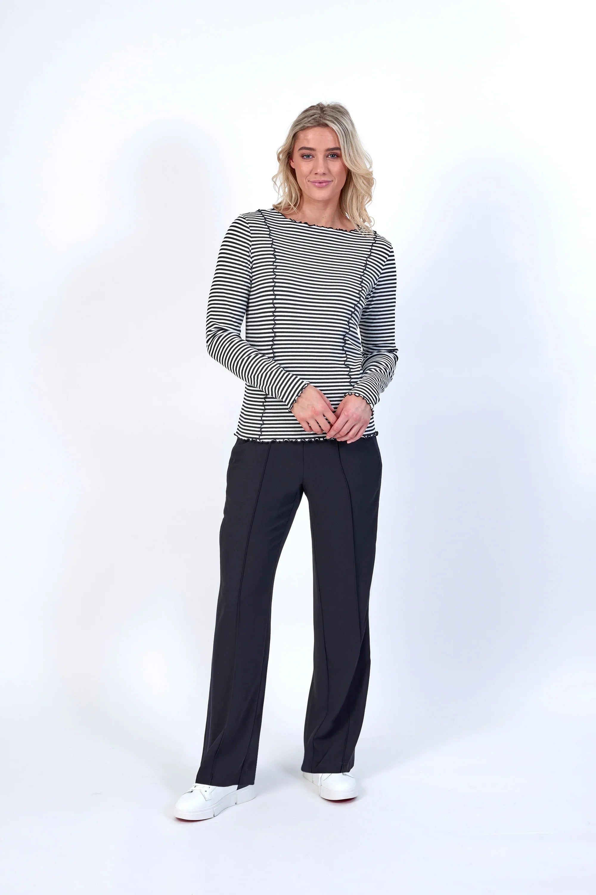 Woman wearing black and white striped long sleeve top with black pants and white sneakers