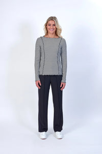 Woman wearing black and off-white striped long sleeve top and black pants