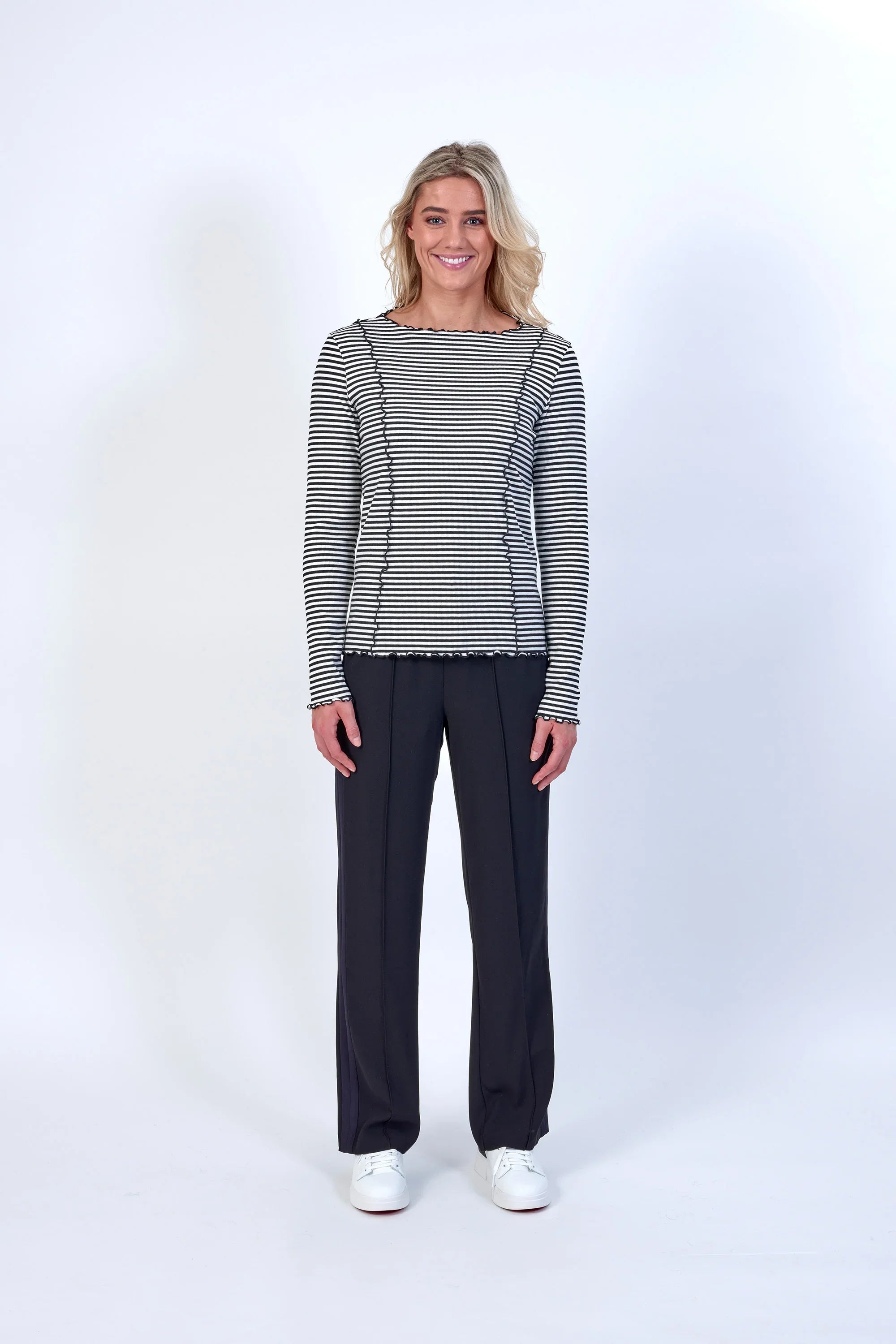 Woman wearing black and off-white striped long sleeve top and black pants