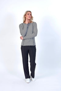 Woman wearing black and off-white striped long sleeve top with black trousers and white sneakers