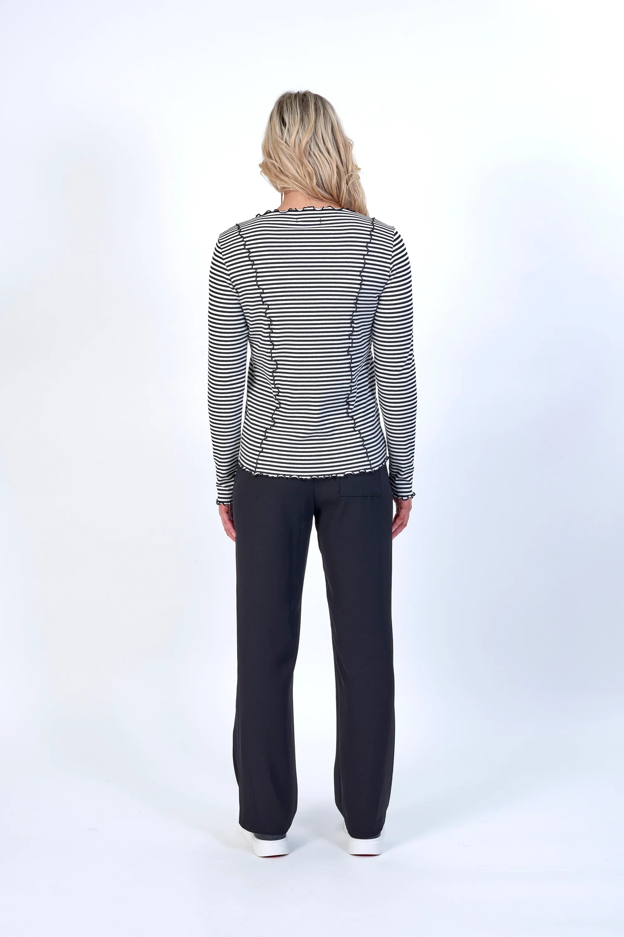 Back view of woman wearing black and white striped long sleeve top and black pants
