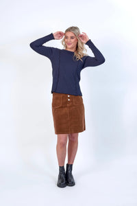 Woman wearing navy long sleeve knit top with brown corduroy skirt and black boots