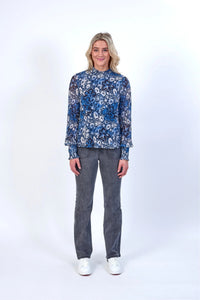 Woman wearing blue floral long sleeve blouse with grey jeans and white sneakers