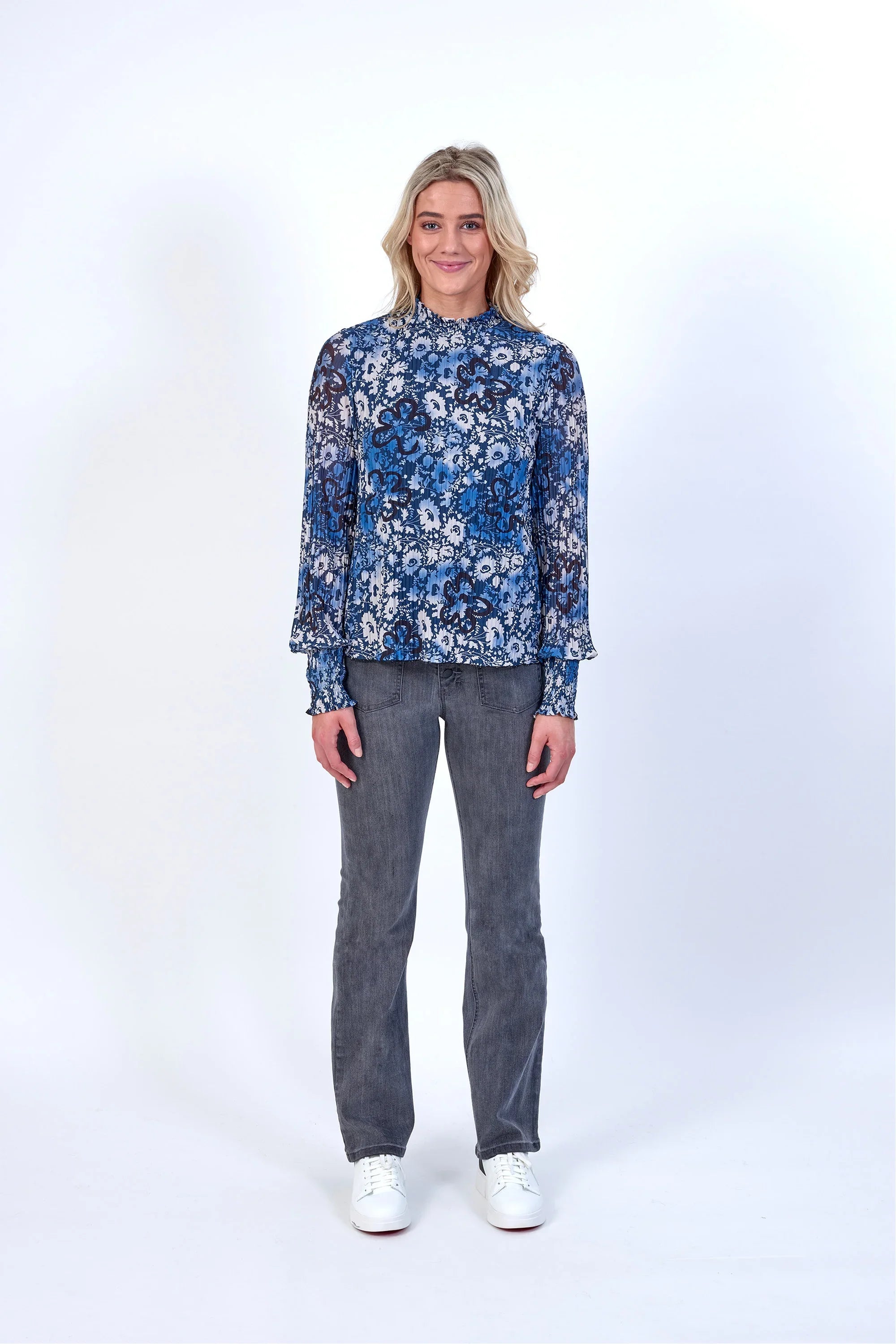Woman wearing blue floral long sleeve blouse with grey jeans and white sneakers