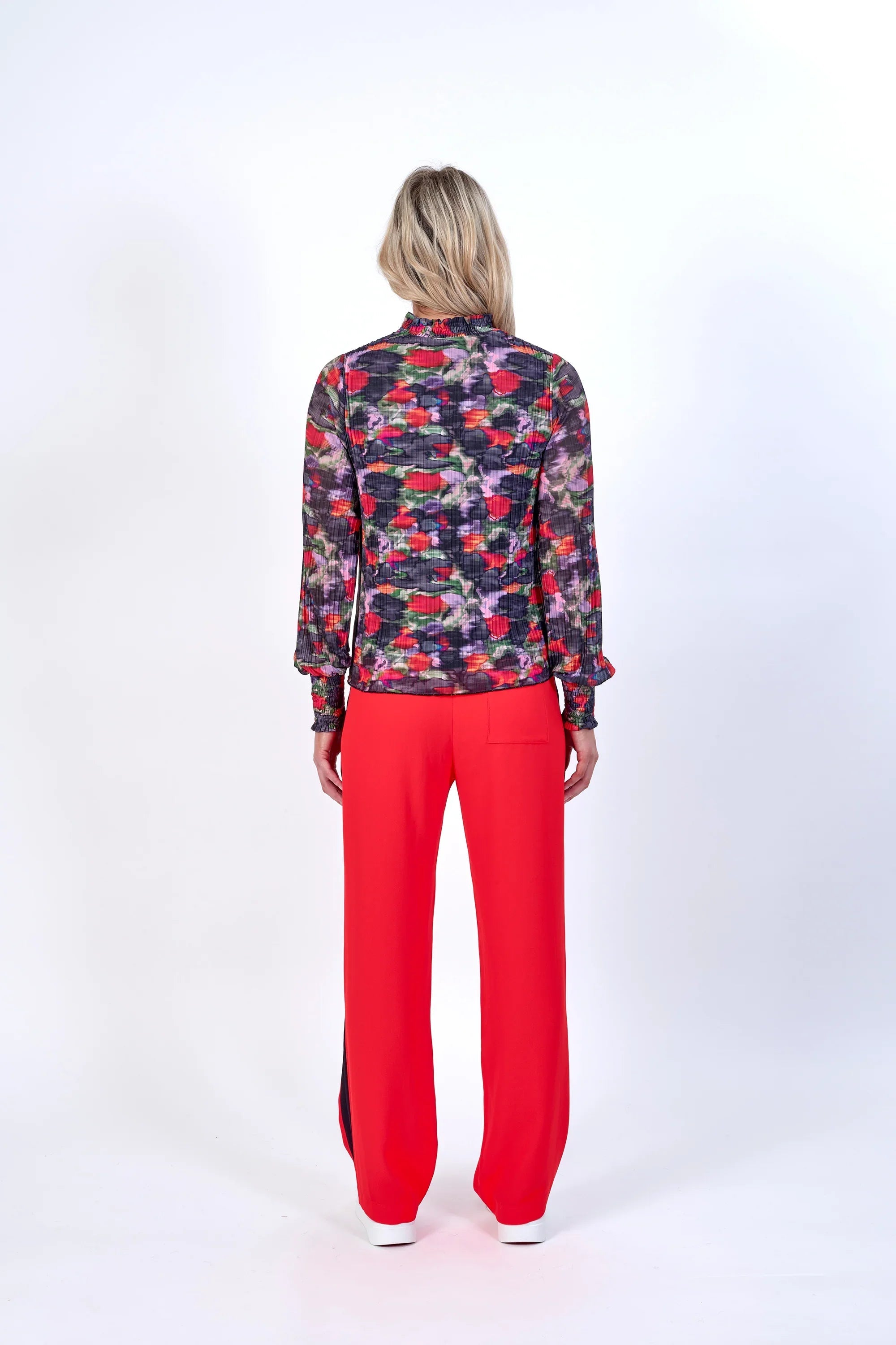 Back view of woman in long sleeve floral print top and bright red wide-leg pants