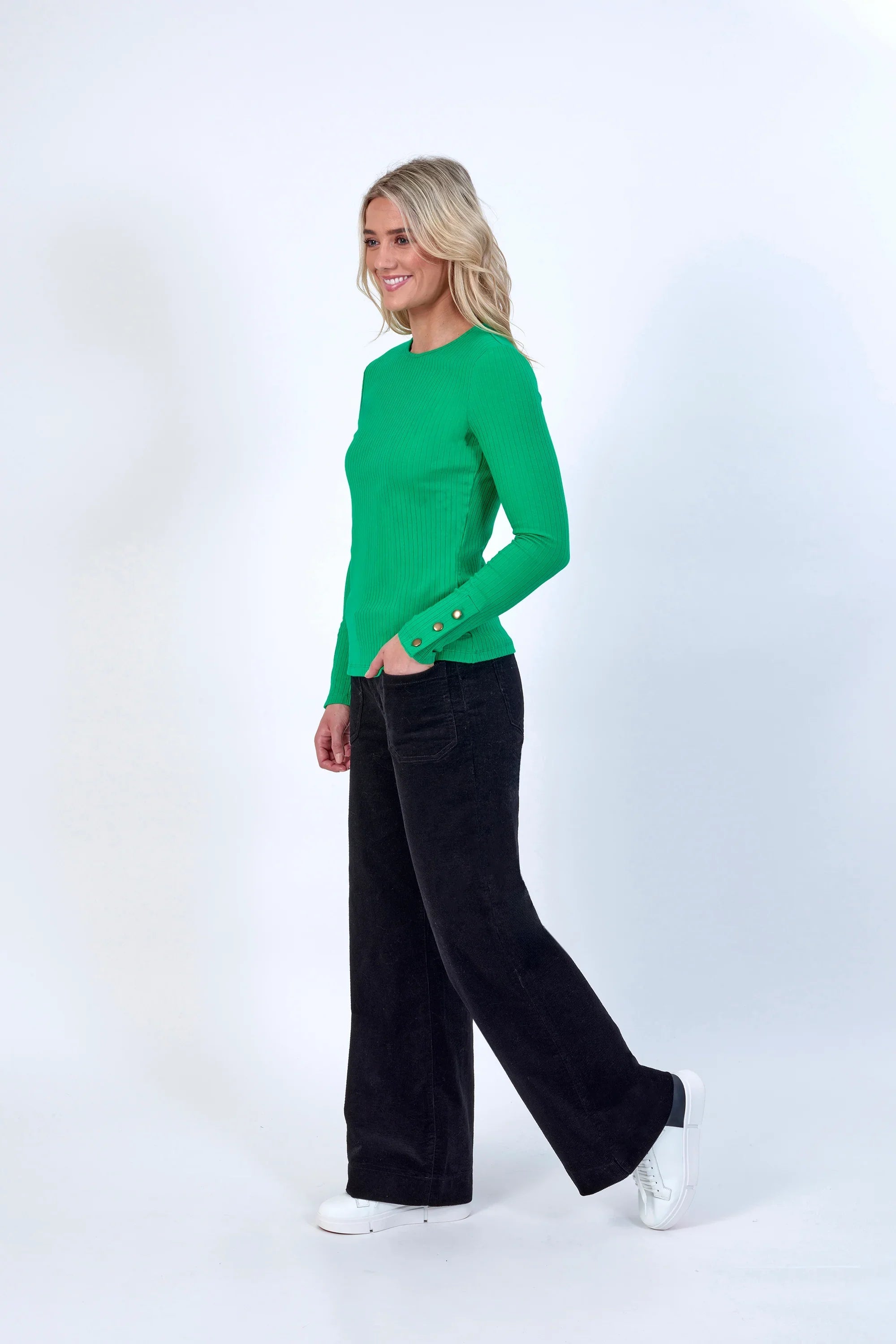 Woman wearing green ribbed long sleeve top and black wide leg pants with white sneakers
