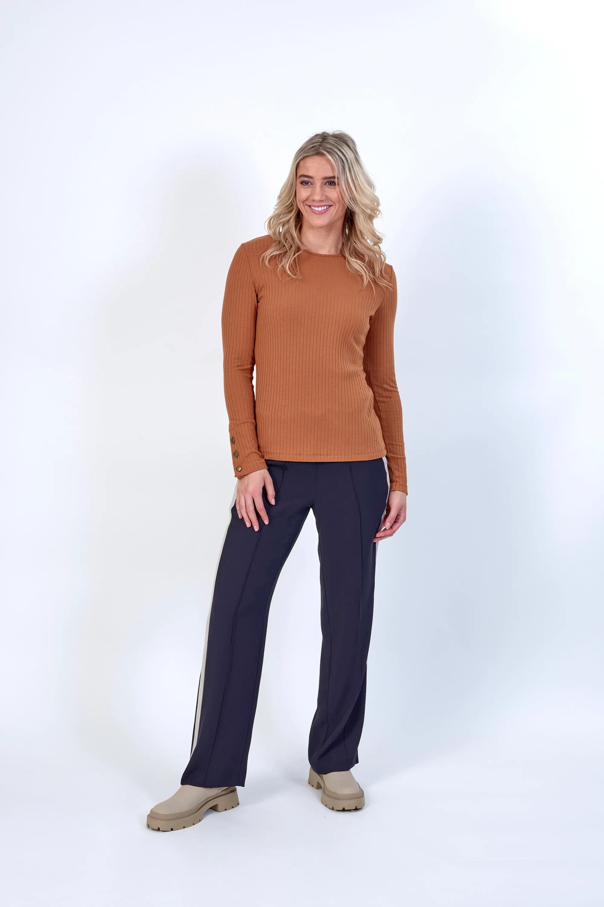 Woman wearing long sleeve ribbed brown top with button details and navy wide-leg pants