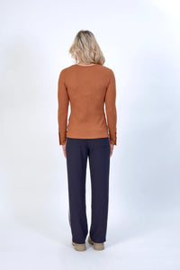 Woman wearing a ribbed brown long sleeve top and navy wide-leg pants, back view