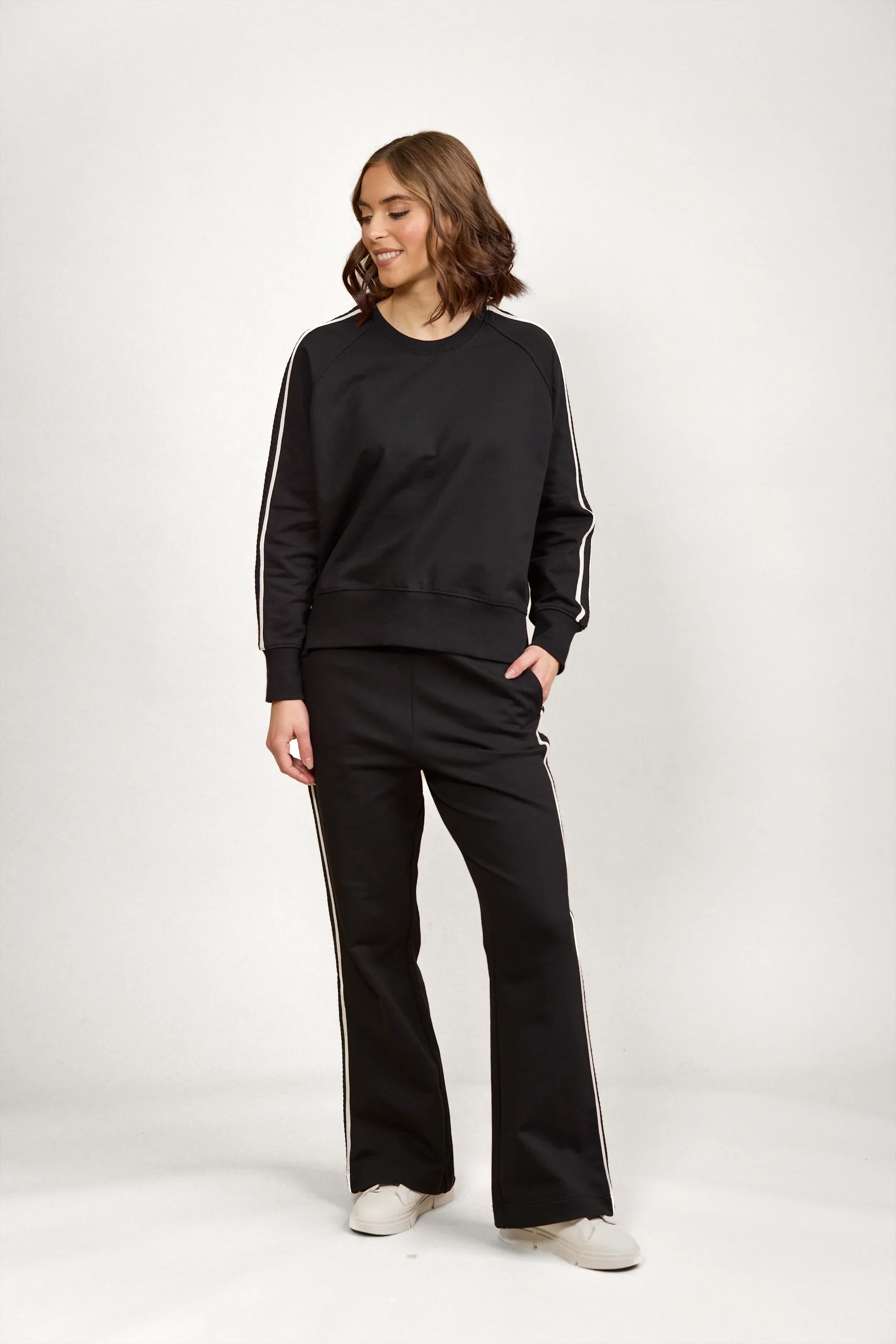 Woman wearing black jumper and pants set with white side stripes, casual fashion outfit