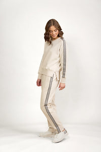 Woman wearing beige knit jumper and pants set with black patterned trim, casual chic fashion