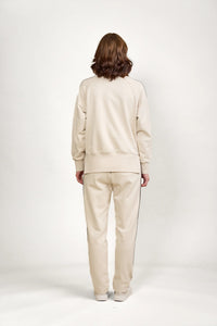 Back view of a woman modeling a beige knit lounge set with long sleeves and pants