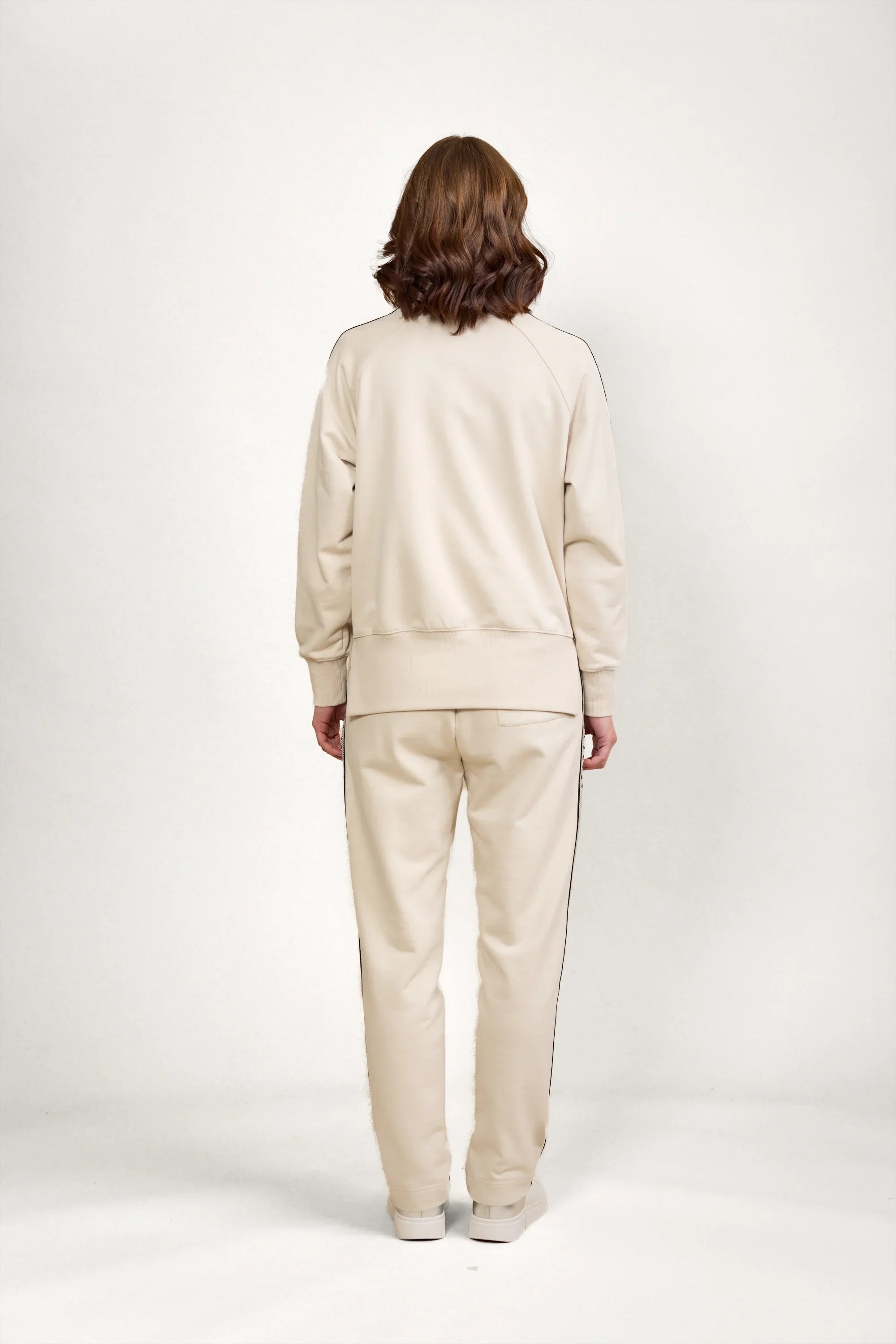 Back view of a woman modeling a beige knit lounge set with long sleeves and pants