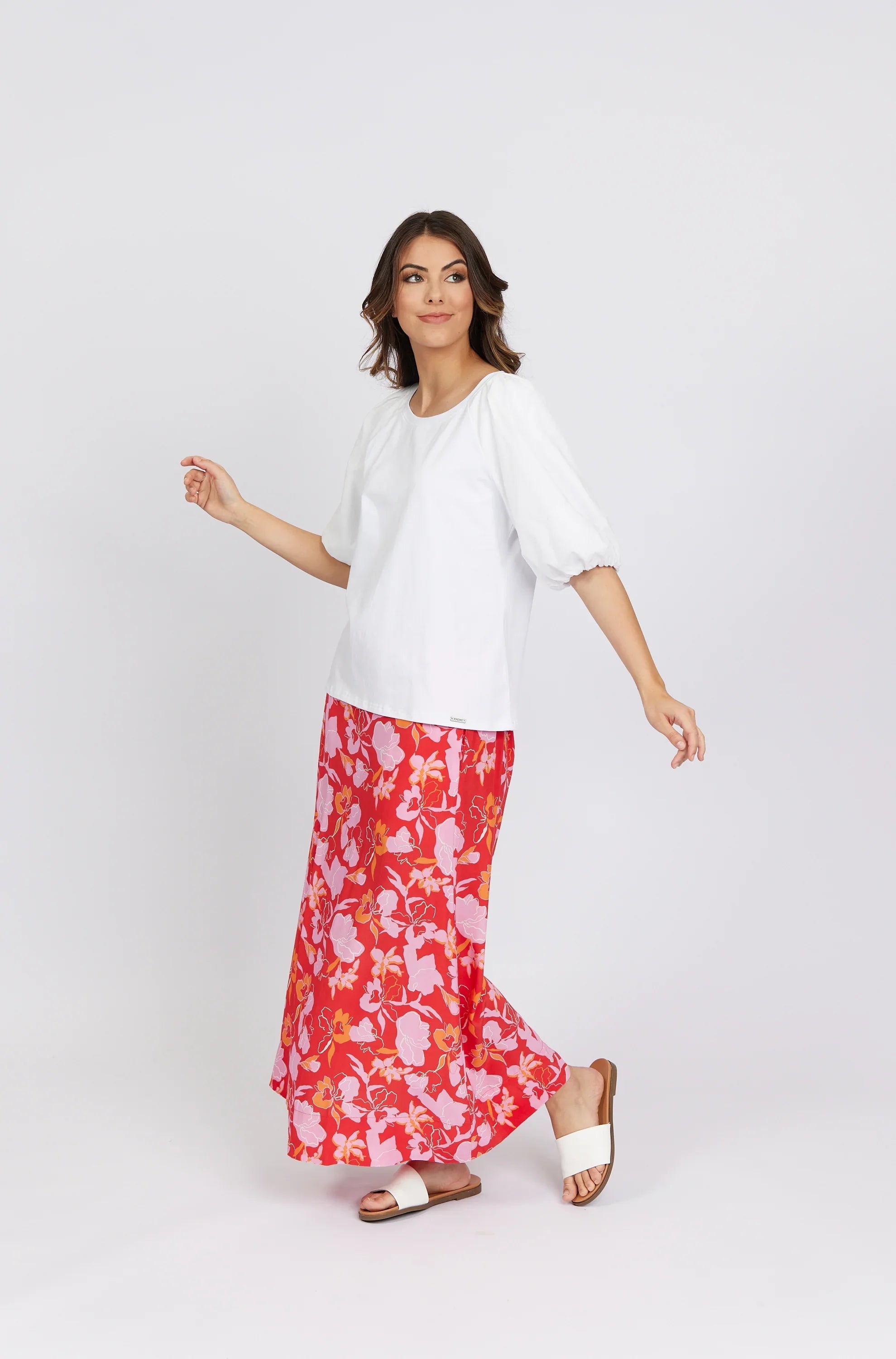 Woman wearing white puff sleeve top and red floral maxi skirt with white sandals
