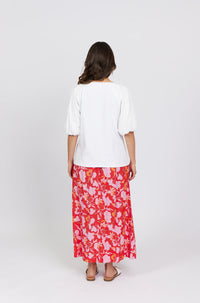 Woman wearing a white puff sleeve top and red floral midi skirt, back view