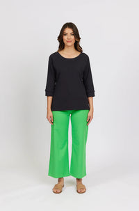 Woman wearing black three-quarter sleeve tee and bright green wide-leg pants