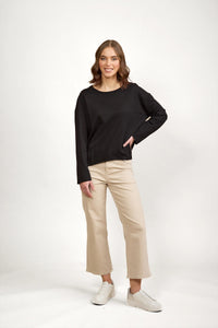 Woman wearing black long sleeve top with beige wide-leg pants and white sneakers