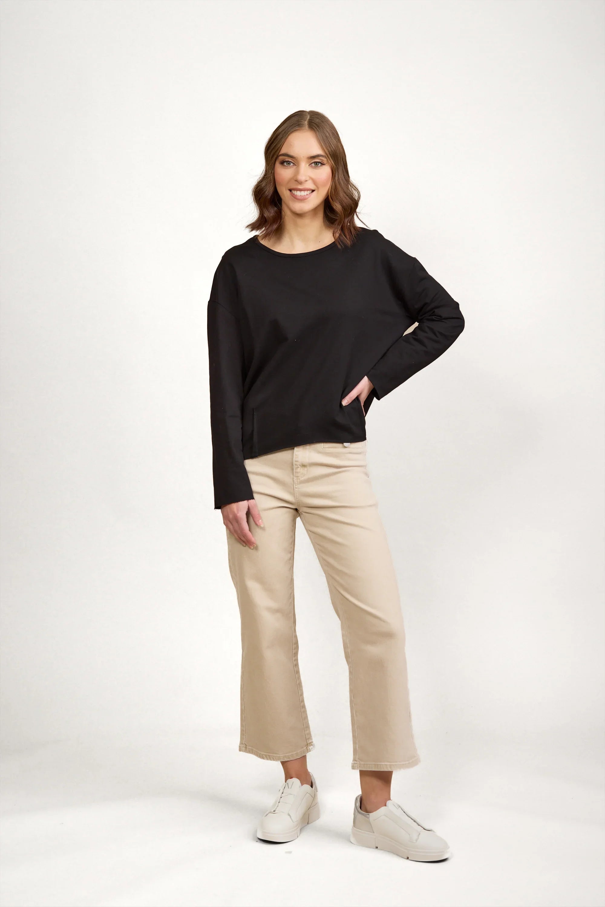 Woman wearing black long sleeve top with beige wide-leg pants and white sneakers