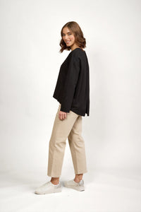 Woman wearing a relaxed black long sleeve top with beige wide-leg pants and white sneakers