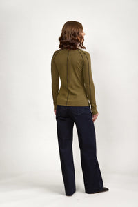 Woman wearing olive long sleeve top with black seam detail and dark wide-leg jeans, back view