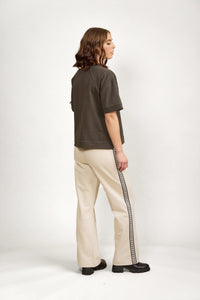 Woman wearing oversized khaki tee and cream track pants with logo side stripe in studio