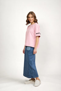 Woman wearing a pink short sleeve tee with zip detail and blue denim maxi skirt, casual style