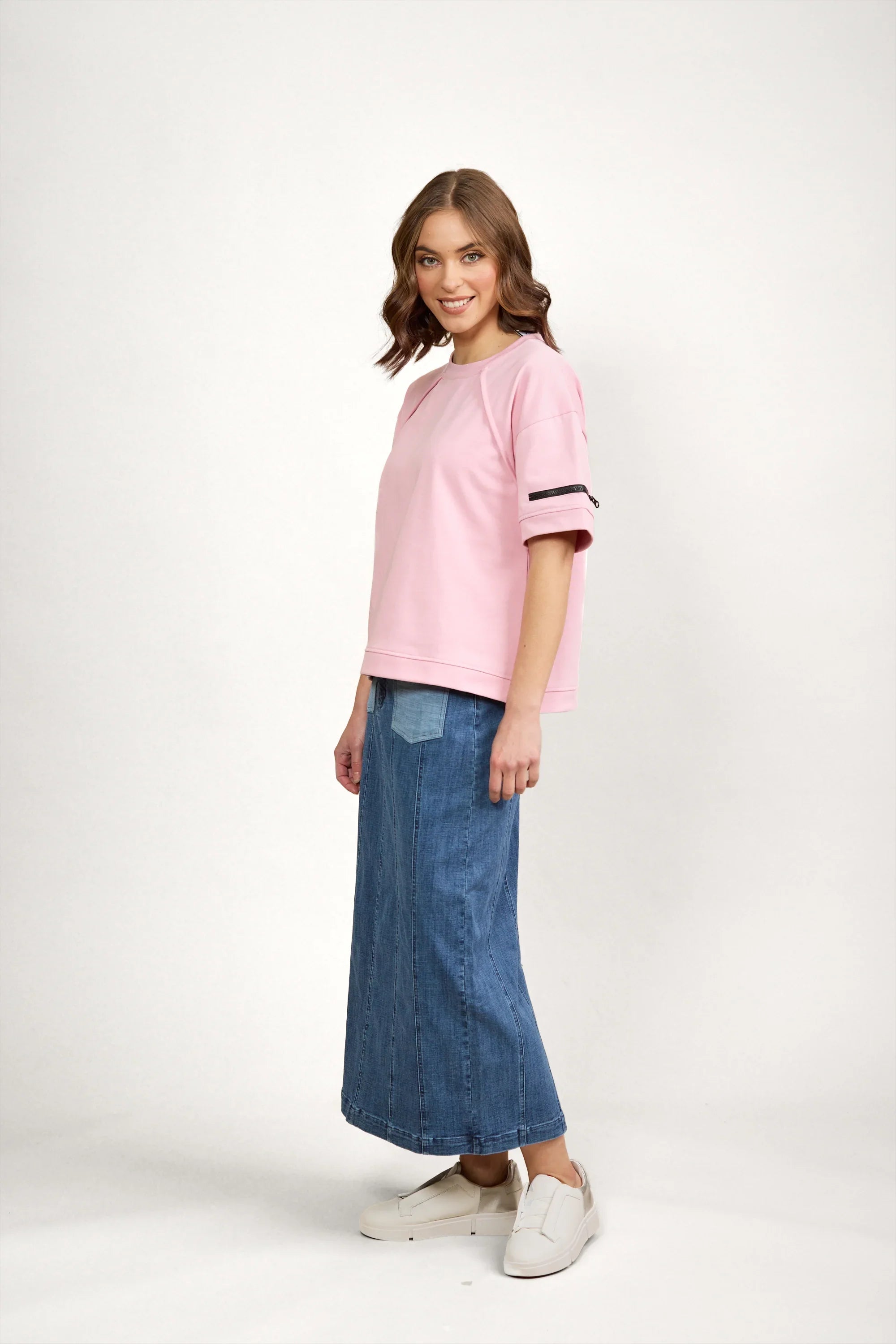 Woman wearing a pink short sleeve tee with zip detail and blue denim maxi skirt, casual style