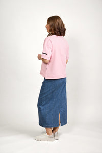 Woman wearing a pink short sleeve tee with zip detail and denim skirt, casual fashion