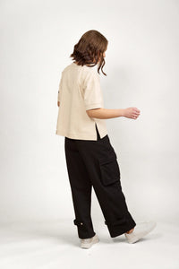 Woman wearing a stone beige short sleeve tee and black cargo pants, side view