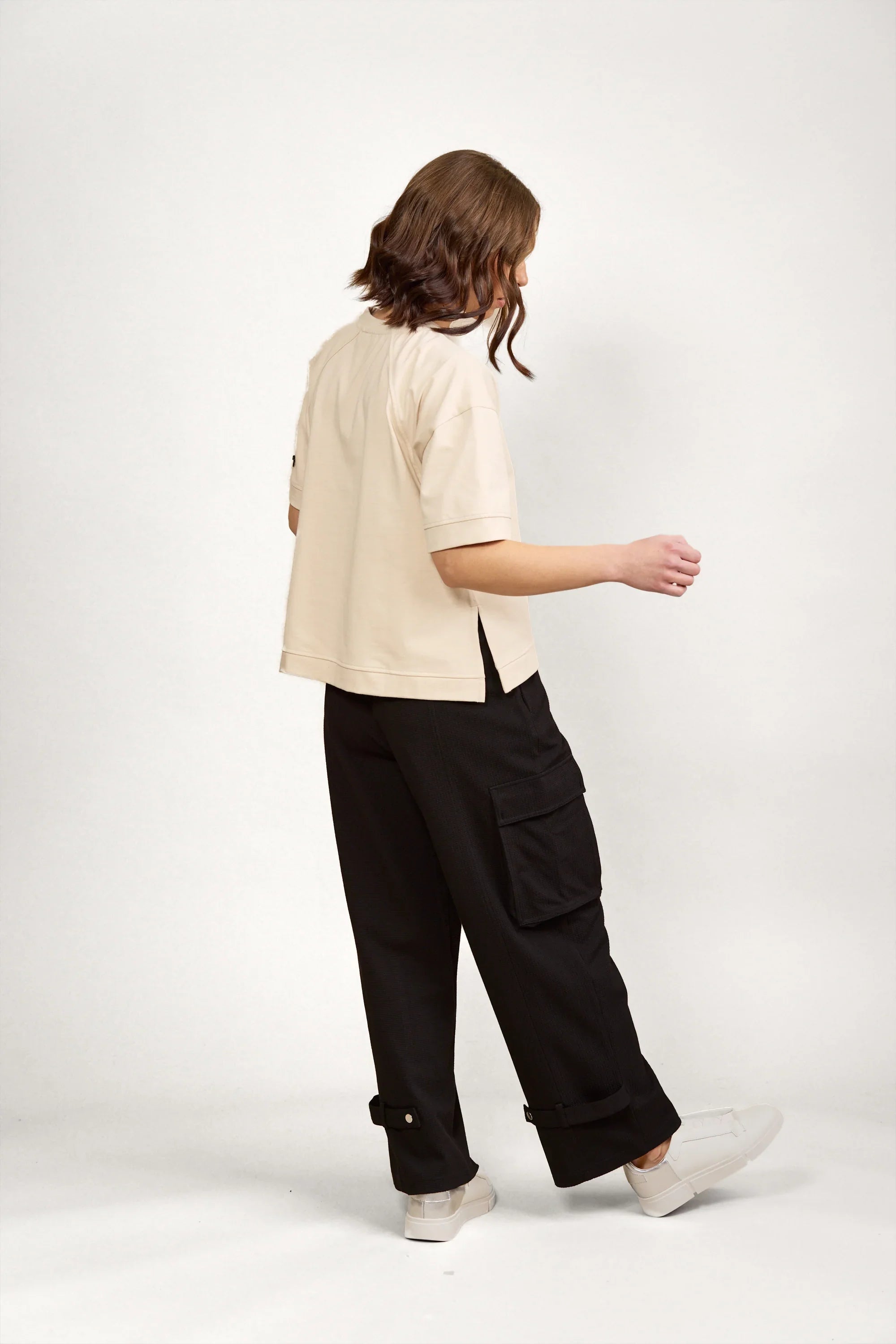 Woman wearing a stone beige short sleeve tee and black cargo pants, side view