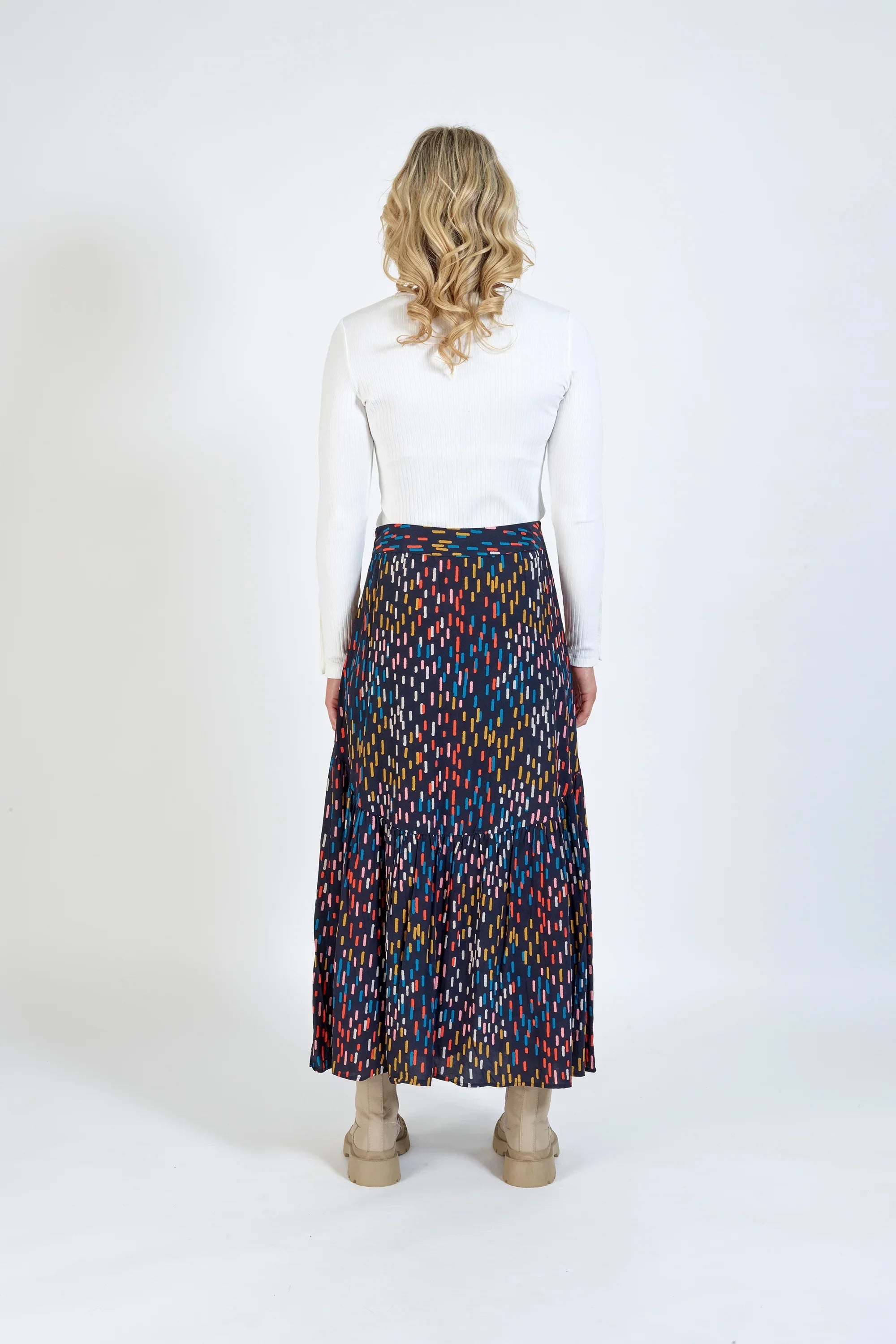Back view of woman wearing colorful patterned maxi skirt and white ribbed top