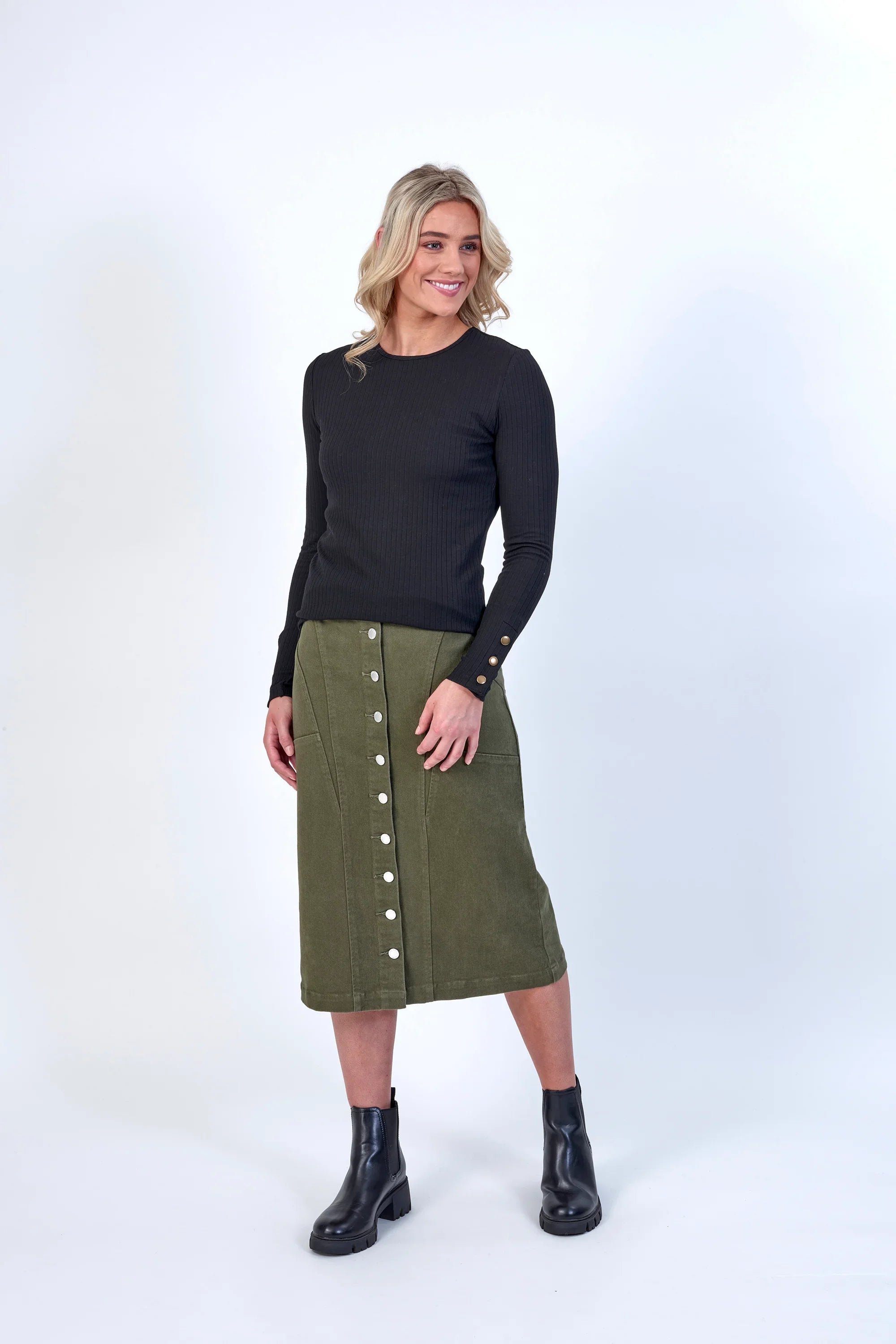 Woman modeling khaki button-front midi skirt with pockets, black ribbed top, and black boots