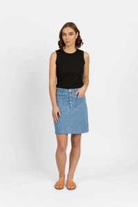 Woman wearing a sleeveless black top and button-front denim skirt with front pockets
