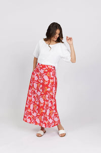 Woman wearing a white blouse and red floral maxi skirt with pink and yellow flowers