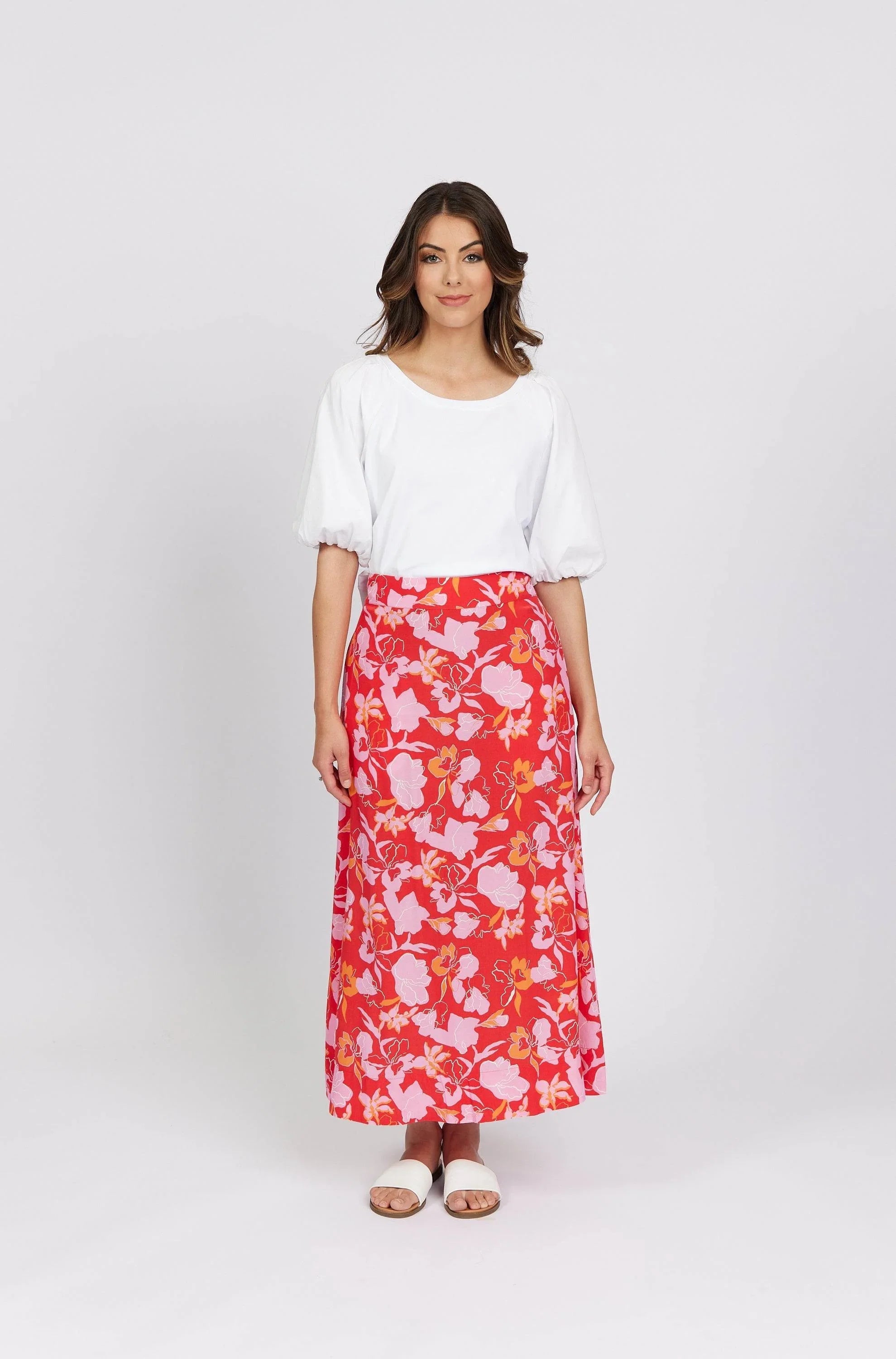 Woman wearing a white puff sleeve blouse and a red floral maxi skirt with sandals