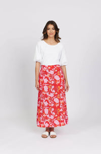 Woman wearing a white puff sleeve blouse and a red floral maxi skirt with sandals