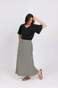 Woman wearing black blouse with geometric print maxi skirt and tan sandals