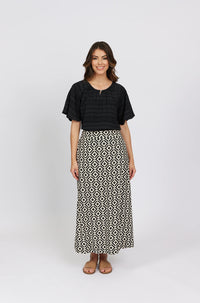 Woman wearing a black short-sleeve blouse and geometric print maxi skirt