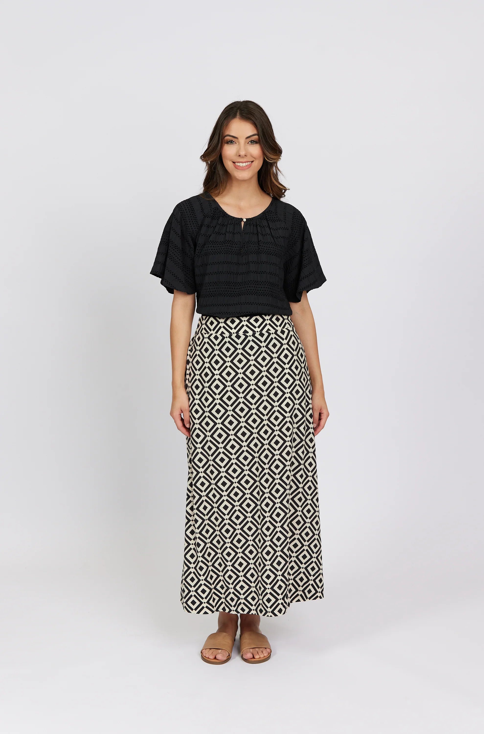 Woman wearing a black short-sleeve blouse and geometric print maxi skirt