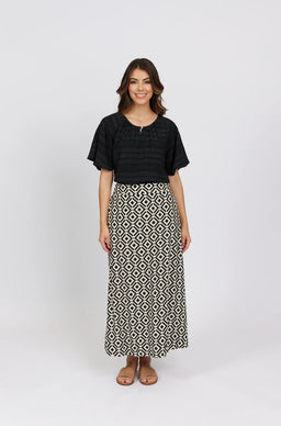 Woman wearing a black short-sleeve blouse and geometric print maxi skirt