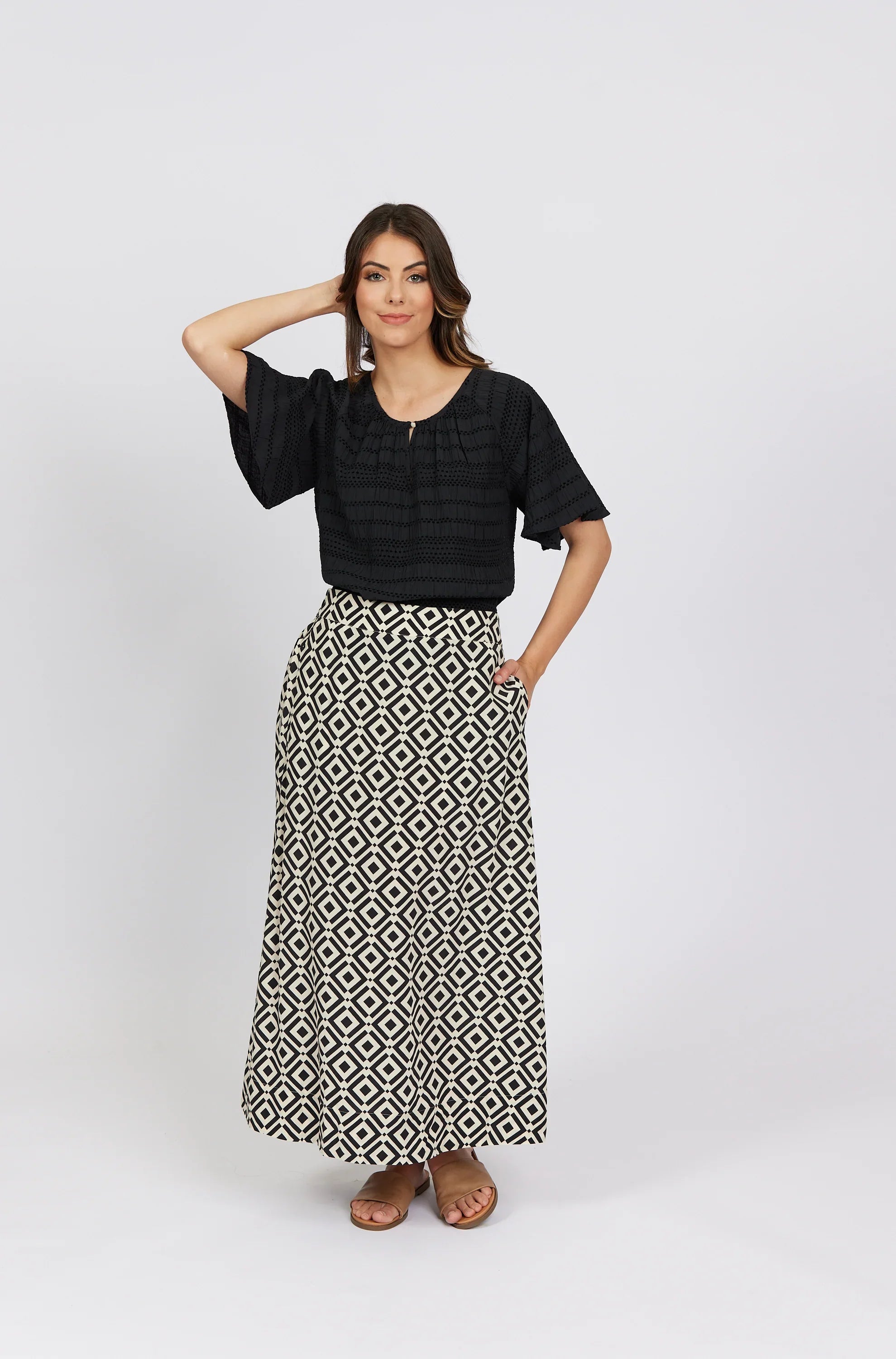 Woman wearing black short sleeve blouse and geometric print maxi skirt with sandals
