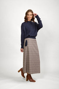 Woman in navy knit sweater and brown check maxi skirt with brown boots