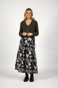 Woman wearing olive buttoned knit sweater and black abstract print maxi skirt with boots