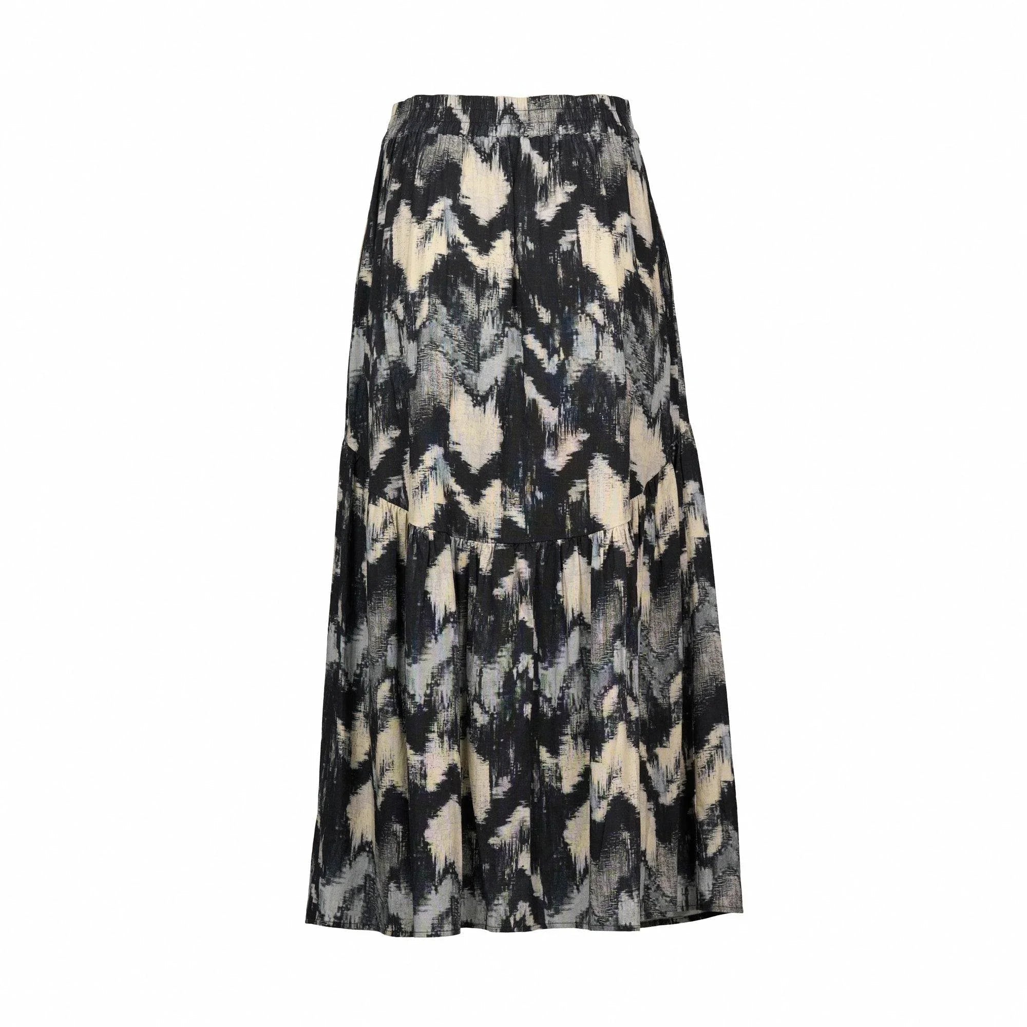 Back view of a black and cream abstract print maxi skirt, tiered and flowy, on white background.