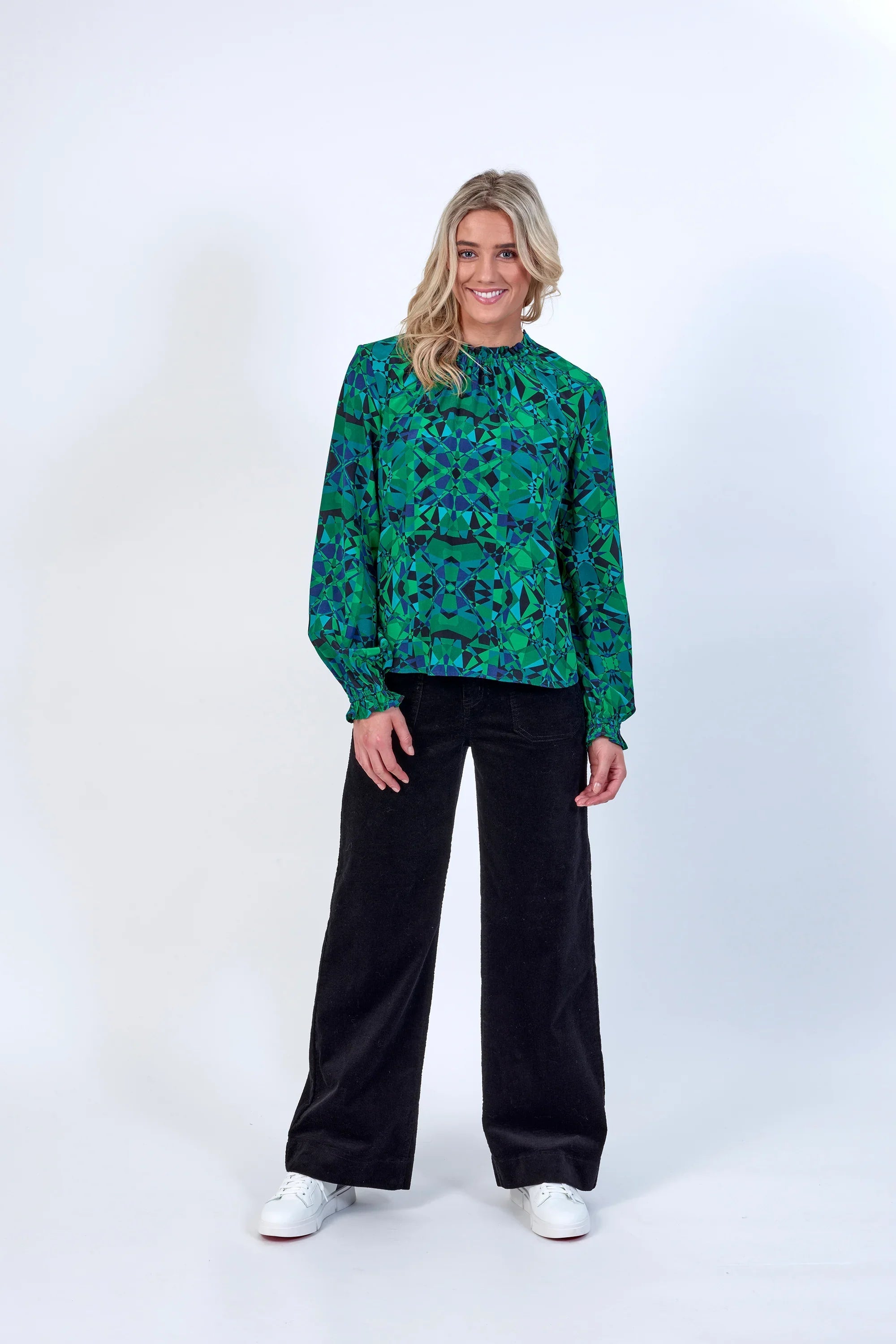 Woman wearing green geometric patterned long-sleeve blouse and black wide-leg pants