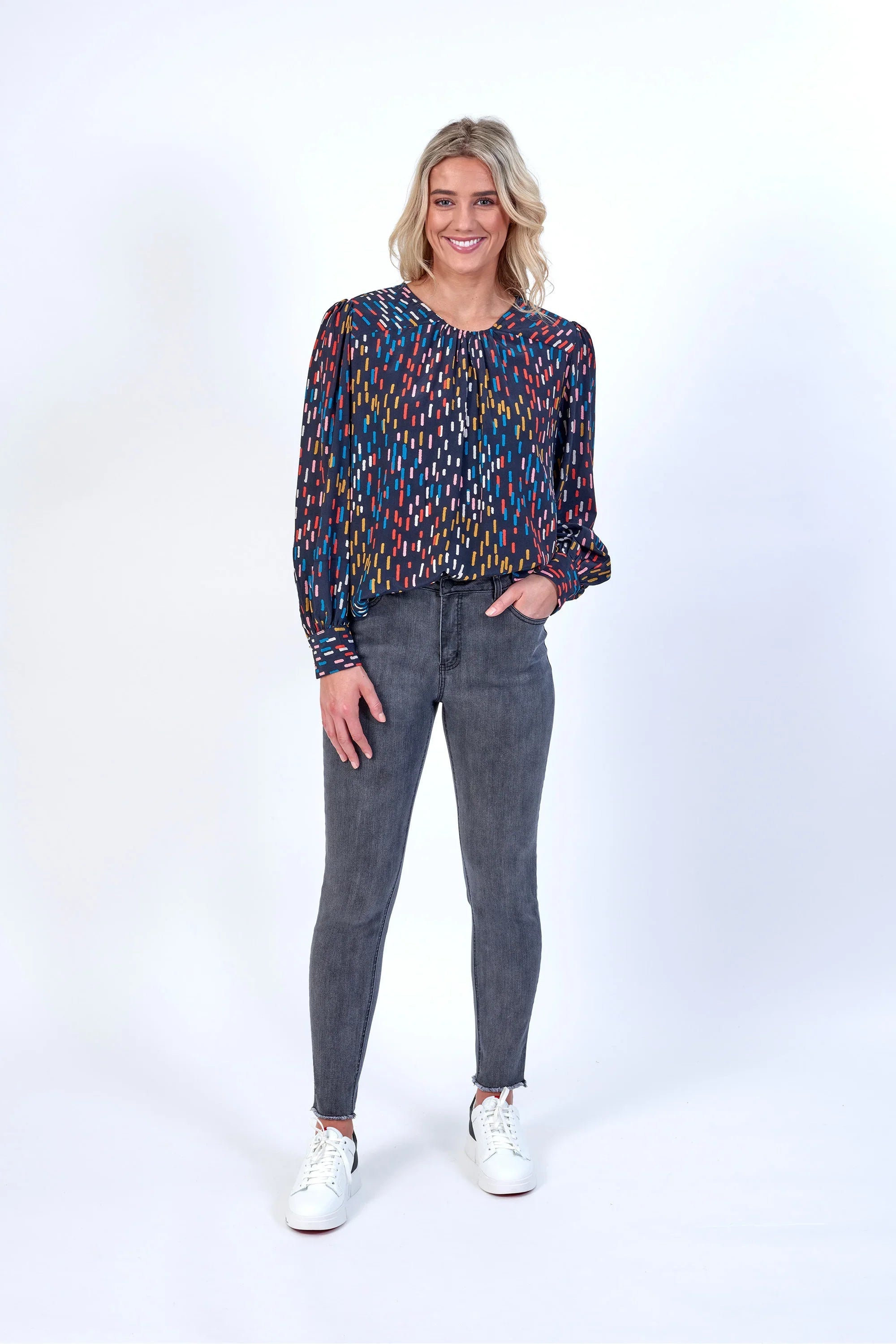 Woman wearing a colorful patterned long sleeve blouse and grey skinny jeans, casual fashion