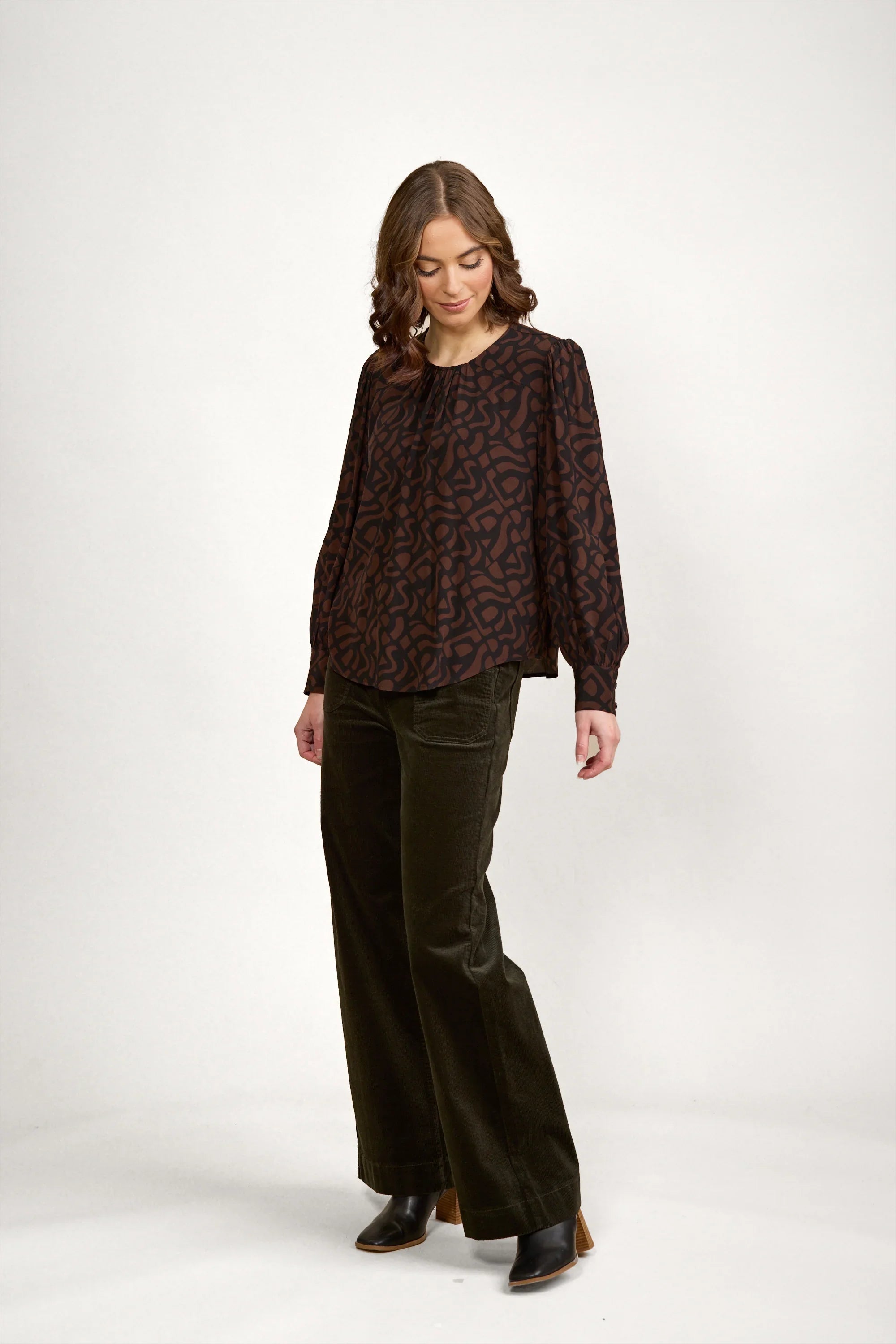 Woman wearing mocha patterned long sleeve blouse with wide leg dark pants and black boots