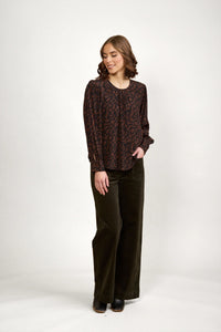 Woman wearing a mocha brown patterned long sleeve top and wide-leg dark pants