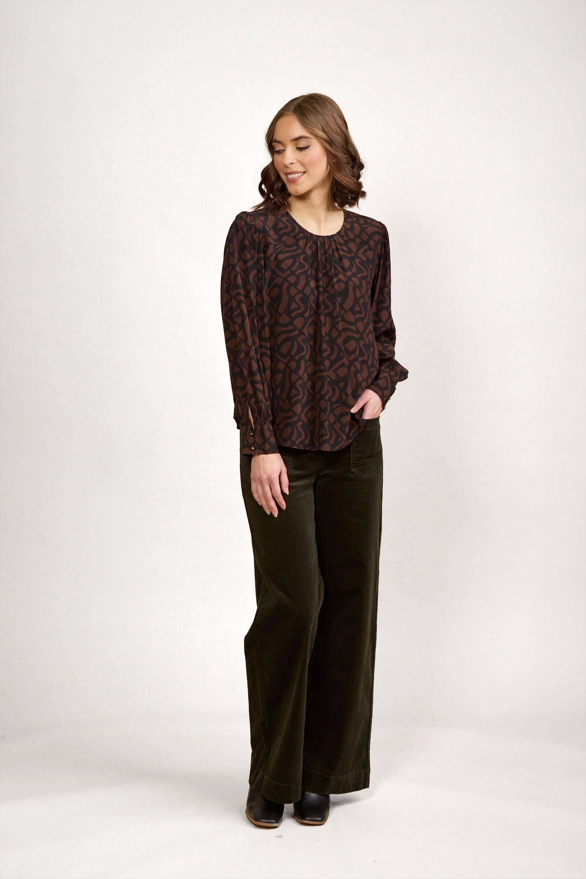 Woman wearing a mocha brown patterned long sleeve top and wide-leg dark pants