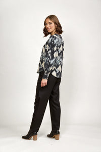 Woman in a long sleeve abstract print blouse with black trousers and ankle boots